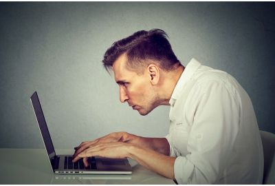 Man hunched over laptop keyboard.