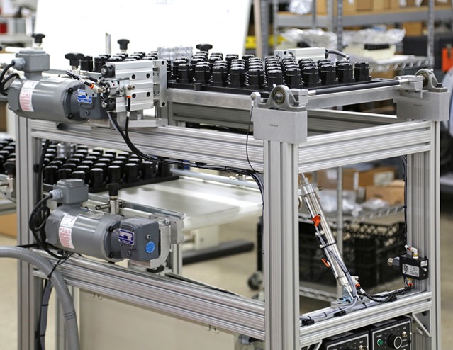 Automated material handling system built with 80/20 T-slot aluminum profiles featuring pneumatic actuators, conveyors, and modular framing for industrial manufacturing and assembly automation.