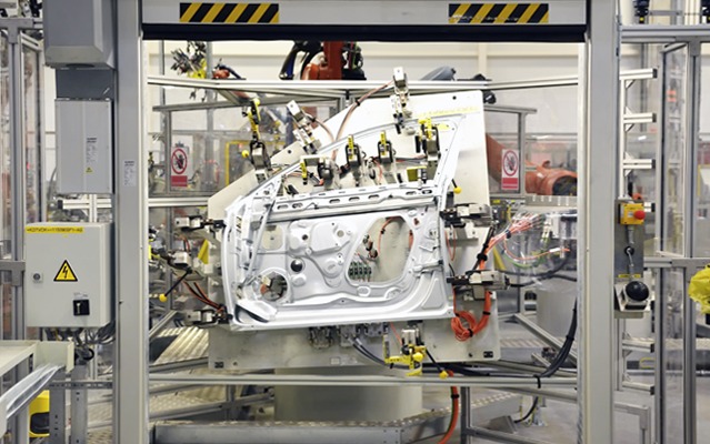 Automotive assembly line with machine guarding around a vehicle door workstation.