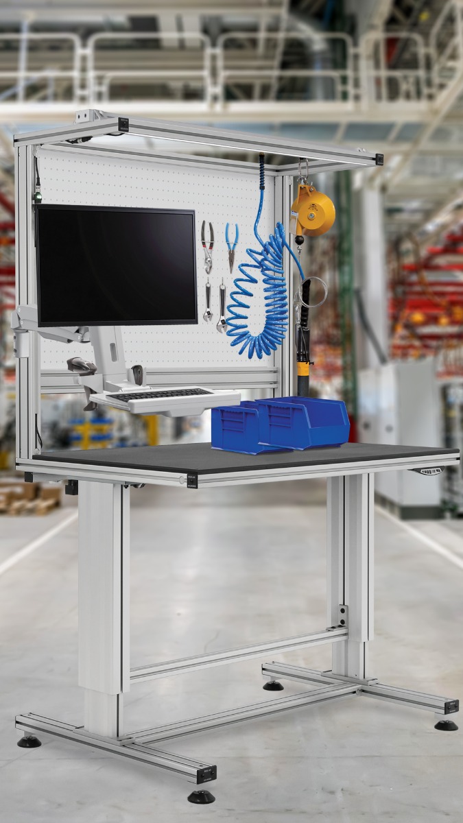 Adjustable T-slot aluminum workstation with monitor arm, air tool, pegboard, bins, and overhead support.