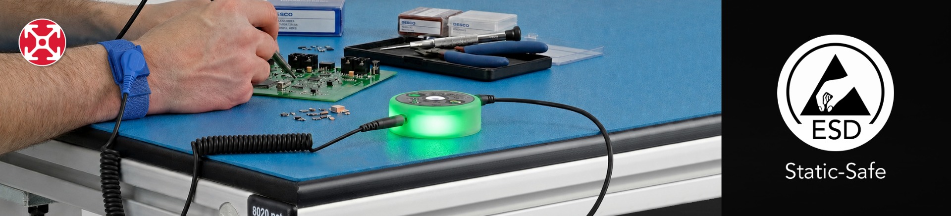 Modular Ergonomic Workstation with Static-Safe ESD Protection Horizontal banner of an 80/20 aluminum workstation featuring a blue ESD-safe table mat, a green-lit DESCO mini monitor, and an operator with a grounding wrist strap. An ESD Static-Safe logo is visible on the right.