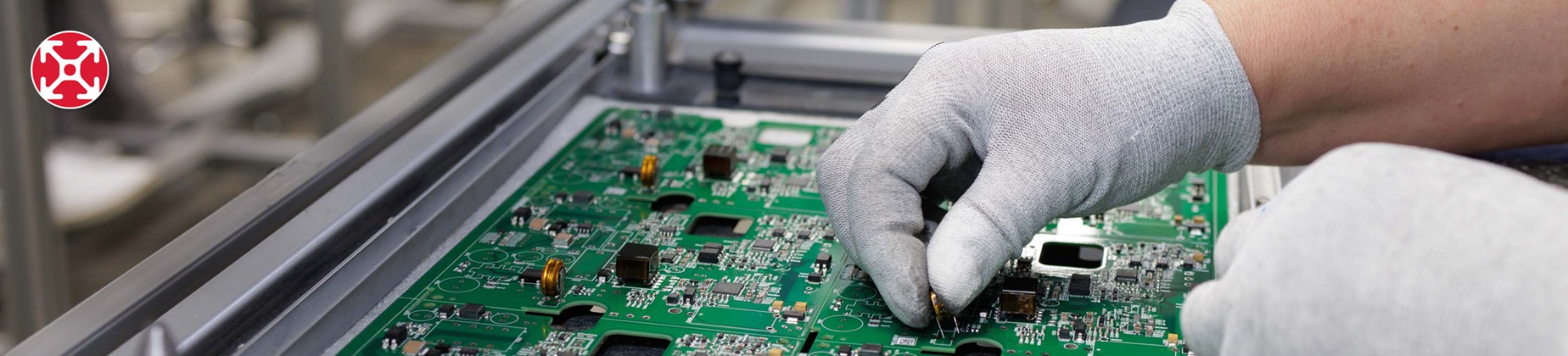 Electronics assembly worker at an ESD-compliant aluminum T-slot workstation placing component on PCB Worker wearing gloves placing an electronic component onto a green printed circuit board while working at an ESD-compliant aluminum T-slot workstation on a factory assembly line.