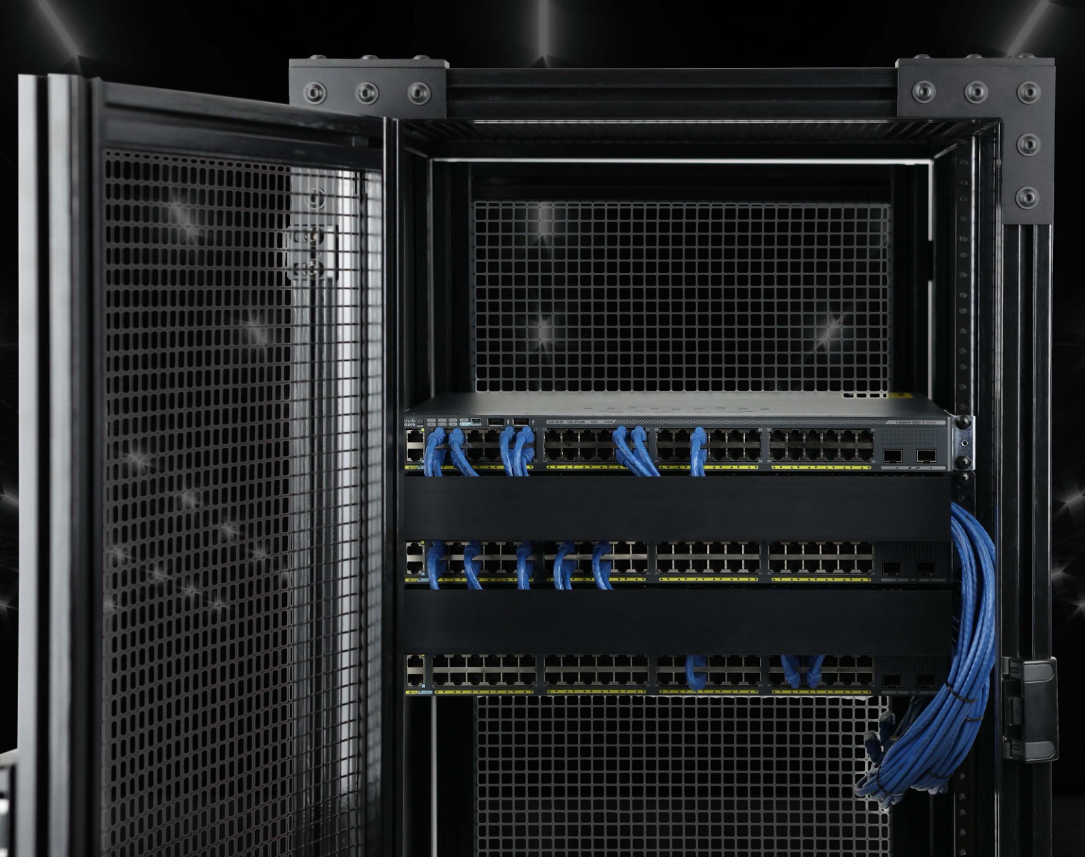 80/20 FRP (Fiberglass Reinforced Polymer) server cabinet. Inside, a high-density network switch is mounted with several blue ethernet cables connected. The black, non-conductive T-slot profiles and mesh door highlights the specialized framing