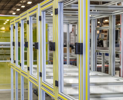 T-Slot Aluminum Machine Guarding & Safety Enclosure Full Assembly | 80/20 Close-up of modular T-slot aluminum machine guarding with clear polycarbonate safety panels and hinged access doors, providing industrial equipment protection, operator safety, and OSHA-compliant manufacturing enclosures.