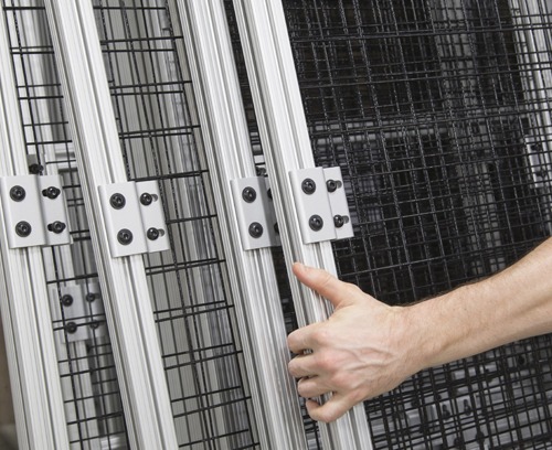 T-Slot Aluminum Machine Guarding Subassemblies with Wire Mesh Panels | 80/20 Worker assembling modular T-slot aluminum machine guarding subassemblies with black wire mesh safety panels, demonstrating easy installation of industrial safety enclosures for manufacturing and automation applications.