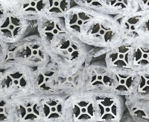 Close-up of 80/20 T-slot aluminum profiles individually wrapped in protective bubble wrap to prevent scratches and damage during storage, packaging, and freight shipping.
