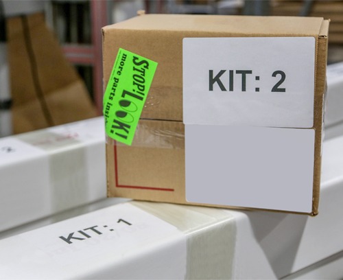 Labeled kit boxes prepared for custom 80/20 T-slot aluminum assemblies, demonstrating organized kitting, order identification, and accurate packaging for efficient installation and shipment.