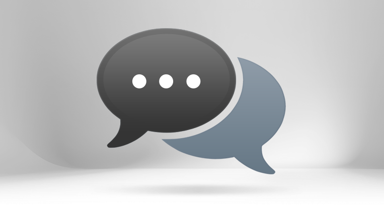 Two overlapping stylized speech bubble icons, one red with three dots and one grey, centered on a dark grey gradient background. The graphic represents live chat support and expert consultation services for custom 80/20 aluminum framing builds.