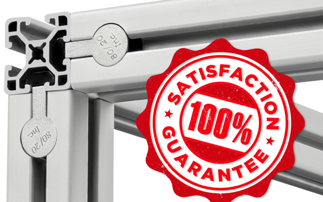 A close-up of a high-quality 80/20 T-slot aluminum frame assembly featuring branded end fasteners. A red "100% Satisfaction Guarantee" badge is prominently displayed over the silver extrusions to highlight product reliability
