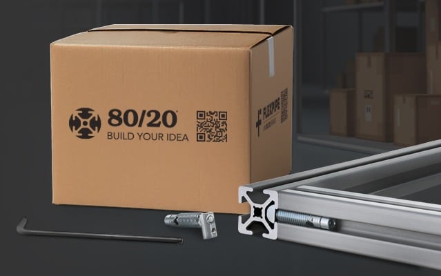 An 80/20 branded cardboard shipping box with the "Build Your Idea" logo and a QR code. In the foreground, a silver T-slot aluminum extrusion is shown with an anchor fastener and a hex key, demonstrating the modular assembly hardware included in a shipment
