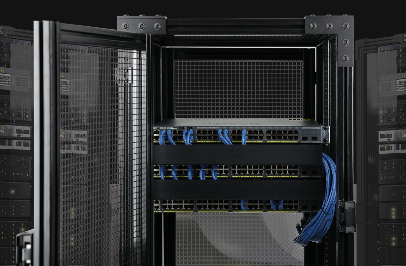 Black 80/20 FRP (Fiberglass Reinforced Polymer) profiles used to construct a secure server rack. The enclosure features wire mesh panels and houses a network switch with blue ethernet cables, illustrating the use of non-conductive framing