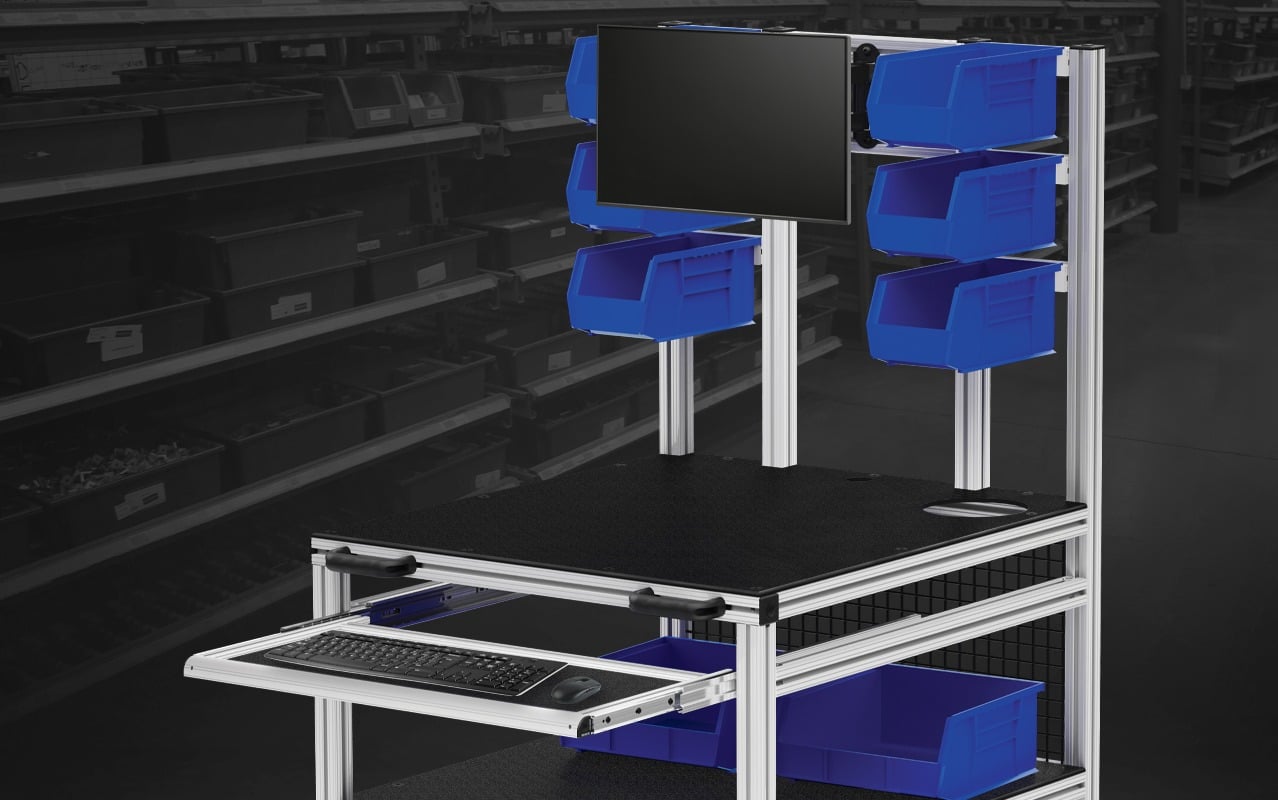 Material handling workstation featuring overhead storage bins, monitor mount, keyboard tray, and aluminum extrusion framing for inventory management, order fulfillment, and production support.