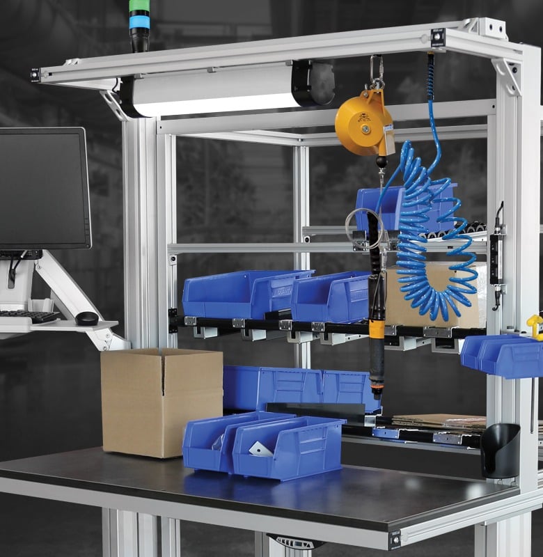 Industrial assembly workstation featuring parts bins, monitor mount, tool balancer, pneumatic tools, and aluminum extrusion framing designed for efficient manufacturing, kitting, and assembly operations.