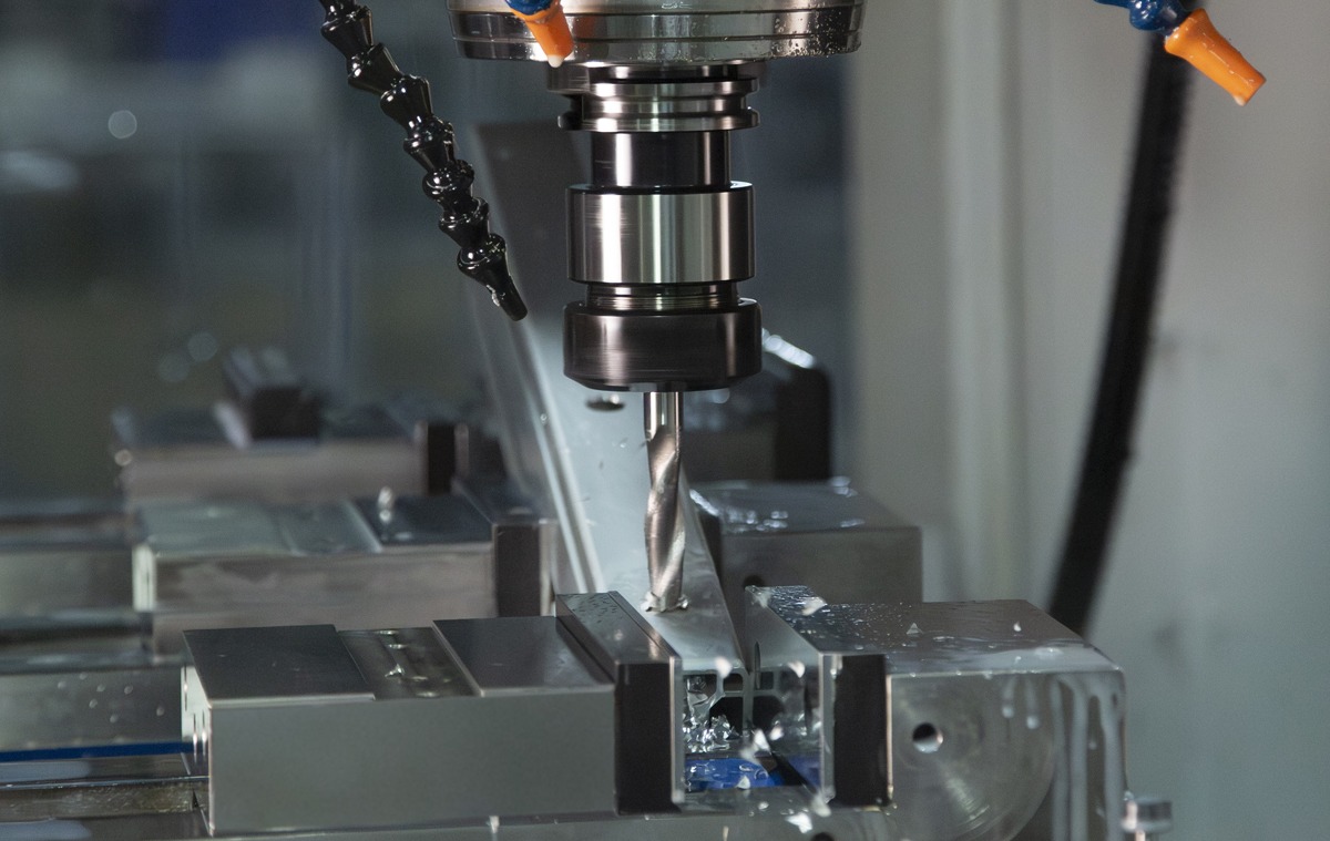 CNC machining center precision-drilling an 80/20 T-slot aluminum profile, showcasing custom machining services for accurate cuts, holes, and end machining in industrial applications.