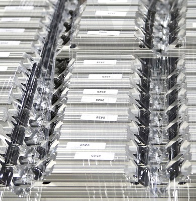 Top-down view of organized 80/20 T-slot aluminum extrusion profiles wrapped in protective clear plastic stretch film for shipping. Each silver profile is labeled and features pre-installed black fasteners, demonstrating industrial fulfillment.