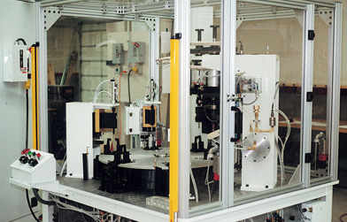 Automated manufacturing equipment enclosed within a clear safety guard made from aluminum extrusions.