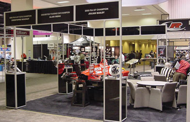 Exhibition booth with aluminum framing, showcasing a red race car and various display materials.