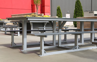 Outdoor installation of aluminum extrusion tables and benches in an industrial setting.
