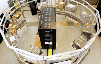 Overhead view of a conveyor system with boxes on belts and a central control unit.