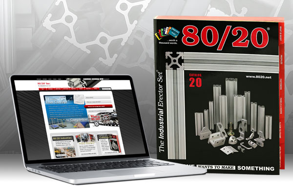 Laptop showing 80/20 Inc. website alongside a printed catalog of industrial erector set products.