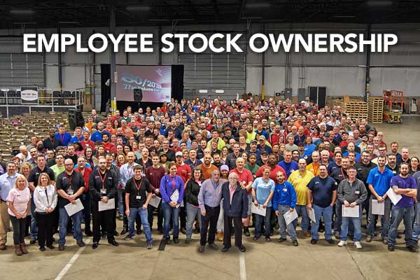 Large group of employees gathered under a banner reading 'EMPLOYEE STOCK OWNERSHIP' inside an industrial facility.