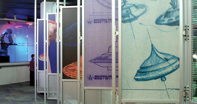 Exhibition space with aluminum extrusion frames displaying engineering and design concept sketches.