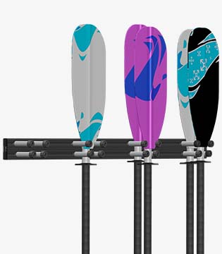 Wall-mounted rack holding three kayak paddles with colorful blade designs in grey, purple, and black, set against a white background.