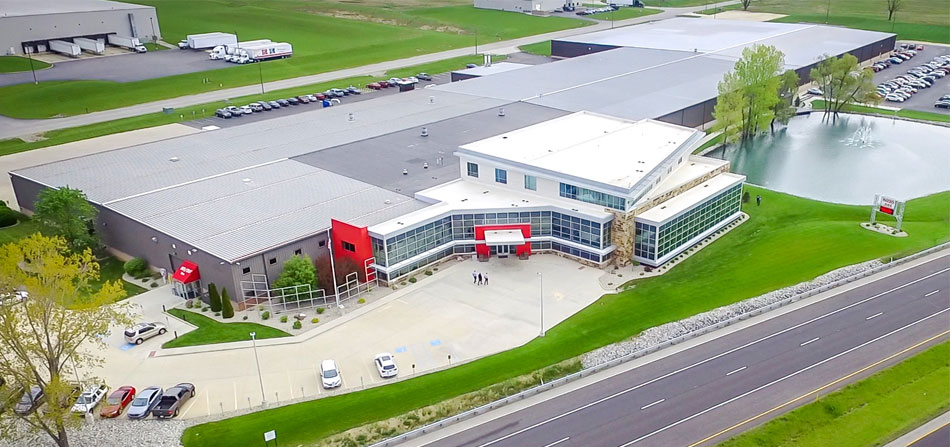 Aerial view of the 8020 building, featuring a modern commercial design with a red entrance and adjacent pond.