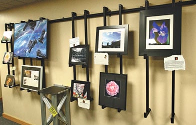 Wall-mounted art display featuring a variety of framed pictures, including space imagery and flowers.