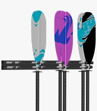 Wall-mounted rack holding three kayak paddles with colorful blade designs in grey, purple, and black, set against a white background.